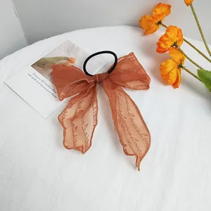 Detail view of the orange chiffon long ribbon bow scrunchie with artistic typography