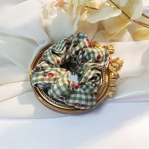 Dettaglio dell'elastico vichy verde con stampe di ciliegie su specchio decorativo