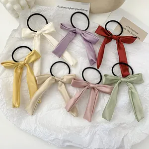 Set of seven colorful satin bow hair ties with long ribbons on white art paper
