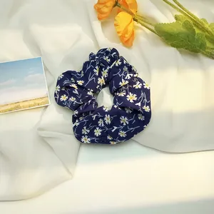 Gros plan du chouchou à fleurs bleu marine avec motif de marguerites sur fond décoratif