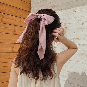 Detail der rosa Haarschleife aus Chiffon mit feiner Naht auf langem welligem braunem Haar