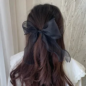 Detail shot of a large black organza bow hair tie worn on wavy long brown hair