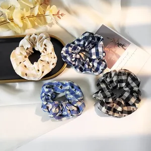 Set of 4 plaid hair scrunchies in cream and blue tones on a minimalist white backdrop
