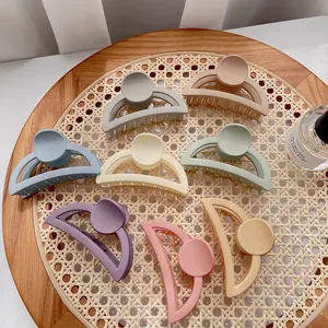 Flat lay of large matte shark hair clips in eight pastel colors on a woven tray