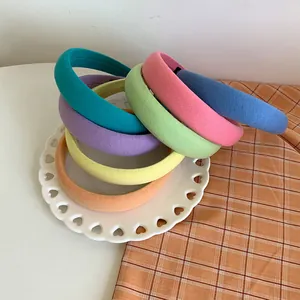 Close-up of assorted candy-colored sponge headbands neatly stacked on a white ceramic tray