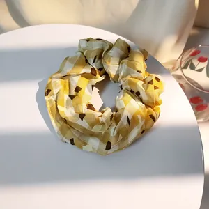 Macro shot of large yellow gingham plaid scrunchie with brown dots on white stand