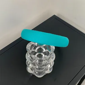 Close-up of bright teal padded sponge headband showing textured knit fabric on glass