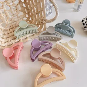 Macro detail of eight matte Morandi colors hair claw clips arranged on a white table