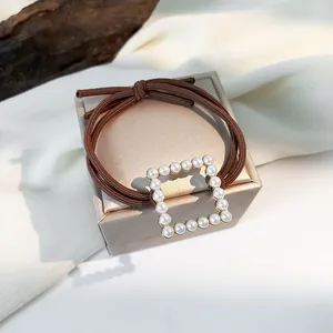 Close-up of brown elastic hair tie featuring a square buckle with white pearls