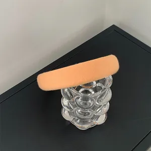 Detail of a thick padded sponge headband in apricot orange fabric on a glass cup