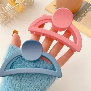 Detail showing pink and blue matte geometric hair claws held in hand for summer styling