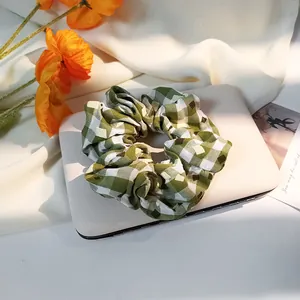 Detail of green and white plaid fabric scrunchie with layered pleats on white tray