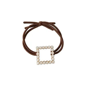 Brown elastic hair tie featuring a square gold base ornament with white pearl inlay