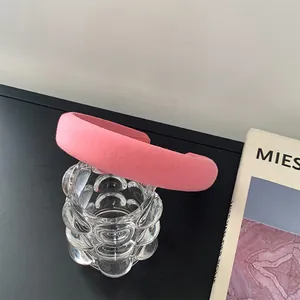 Close-up of pink padded sponge headband against a minimalist glass and book backdrop