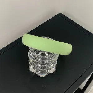 Detail of light green thick sponge headband with soft knit texture on glass stand