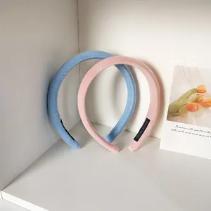 Nahaufnahme von gepolsterten Cord-Stirnbändern in Hellblau und Rosa mit Etiketten
