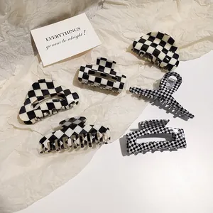 Flat lay of six acetate hair claws featuring classic black and white checkerboard patterns