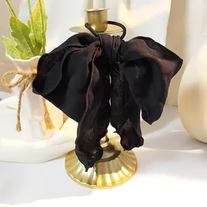 Detail eines eleganten schwarzen Chiffon-Haargummis auf einem goldenen Ständer
