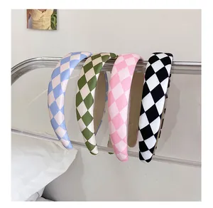 Detailed view of checkered sponge headbands in blue, green, pink, and black on a clear stand
