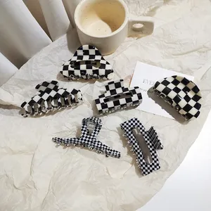 Flat lay of six geometric black and white checkered acetate hair claws on textured paper