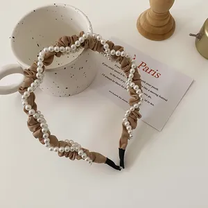Detail view of a French retro headband with brown pleated fabric and white pearls