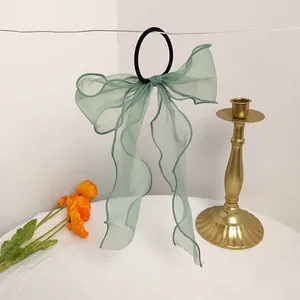 Detail of mint green organza bow hair tie with long ribbons hanging on white background