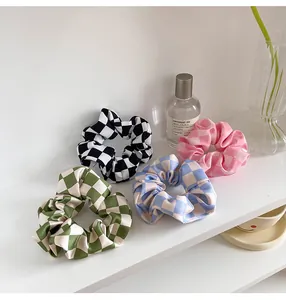 Detailed view of four satin checkered scrunchies in green, black, blue, and pink colors