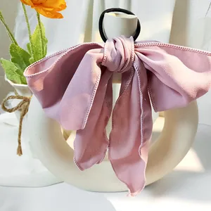 Detail eines zartrosa Haargummis mit Chiffon-Schleife, langen Bändern und schwarzem Gummiband
