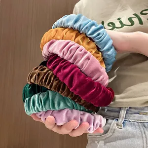 Set de diademas de terciopelo plisado en varios colores sostenidas sobre fondo de madera