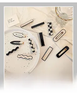 Flat lay of black and white checkerboard acrylic hair clips on a white ceramic plate