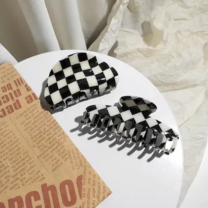 Detail view of two black and white checkerboard acetate hair claw clips for women