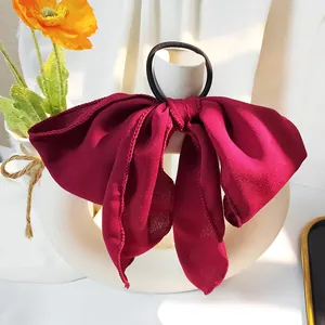 Nahaufnahme eines weinroten Haargummis mit Schleife und feiner Chiffon-Struktur am Rand