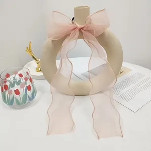 Detail of light pink organza bow hair tie with long ribbons on a beige vase