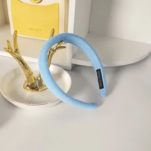 Detail eines hellblauen gepolsterten Stirnbands mit Rippstoff und handgefertigtem Etikett