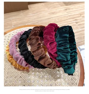 Vista plana de diademas de terciopelo plisado en varios colores sobre bandeja tejida