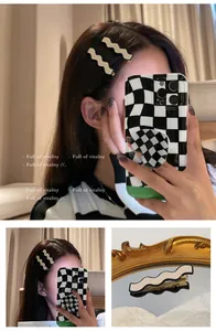 Detail shot of wavy black and white checkerboard hair clips with a high-gloss finish