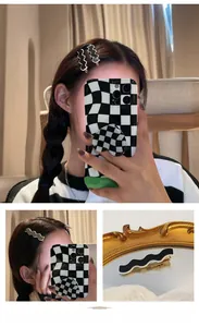 Detail of a curved checkerboard hair clip in black and white acrylic finish