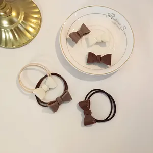 Close-up of cream and brown bow hair ties and clips on a gold-rimmed china plate