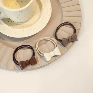 Three-piece set of cream and brown bow hair ties displayed on a vintage aesthetic tray