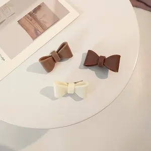 Detailed view of three acrylic bow hair clips in cream, brown and coffee colors