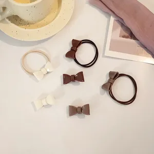 Detail of glossy acrylic bow hair ties and clips in cream brown and taupe colors