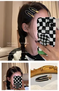Close-up of matte black acrylic checkerboard hair clips on hair and mirror detail