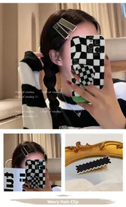 Detailed view of black and dark green wavy hair clips with white trim on a mirror