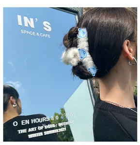 Dettaglio della clip per capelli in peluche bianca con orsetti blu sulla chioma