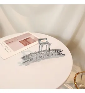 Detalle de la pinza para el cabello de metal plateado con letras artísticas troqueladas