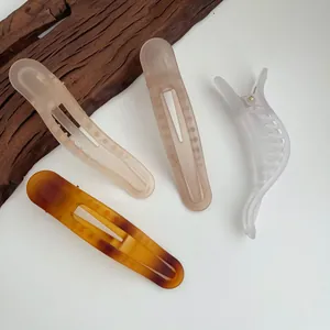 Dettaglio di fermagli per capelli opachi beige, rosa e tartarugati su vassoio di legno