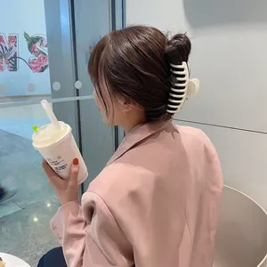 Pinza de pelo grande mate blanco crema sujetando un moño en el cabello castaño