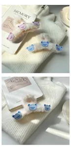 Dettaglio della molletta in peluche crema con graziose toppe a forma di orsetto viola e blu