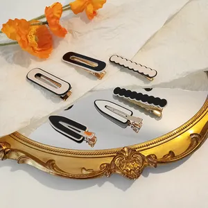 Detail of six black and white checkered acrylic hair clips on a vintage mirror surface