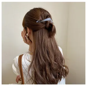 Matte grey banana clip securing a half-up hairstyle on long wavy brunette hair